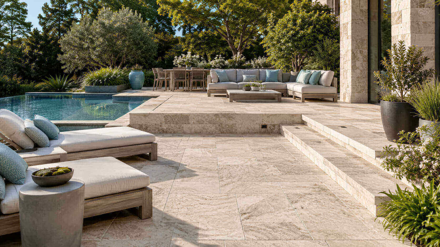 Luxury outdoor living area with natural stone patio, pool surround, steps, and landscaped seating spaces.