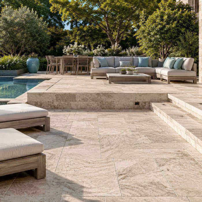 Luxury outdoor living area with natural stone patio, pool surround, steps, and landscaped seating spaces.