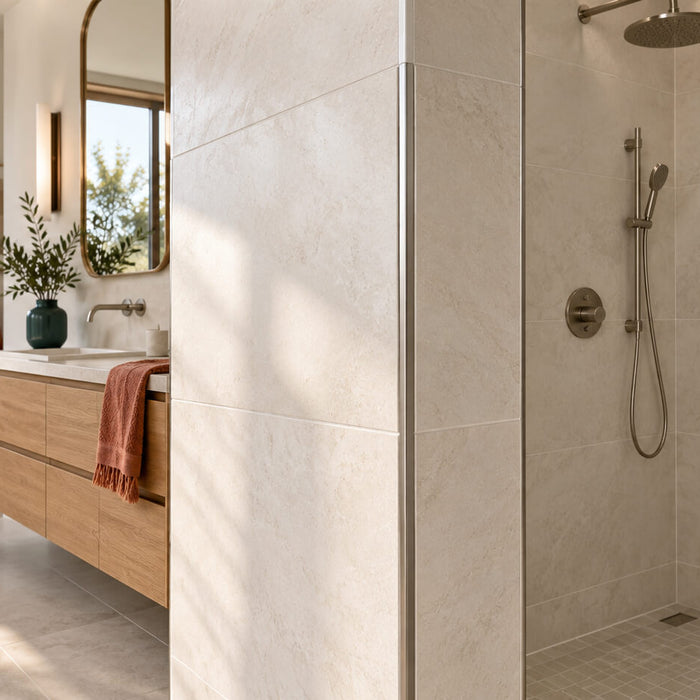 Sunlit bathroom with ivory tiled shower walls, a metal edge profile, a recessed niche, and a floating oak vanity.