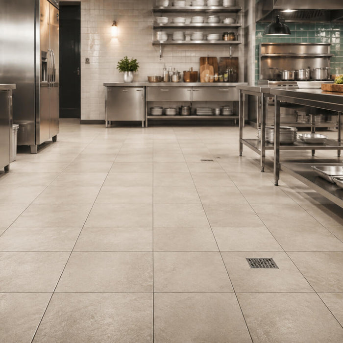 Commercial kitchen with durable beige floor tile, stainless steel workstations, and integrated floor drainage