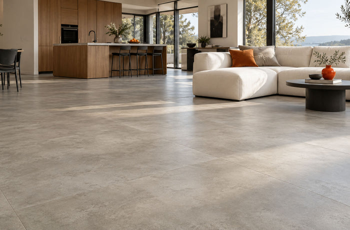 Modern kitchen and living room with matte concrete-look vinyl flooring, oak cabinets, and a cream sofa.