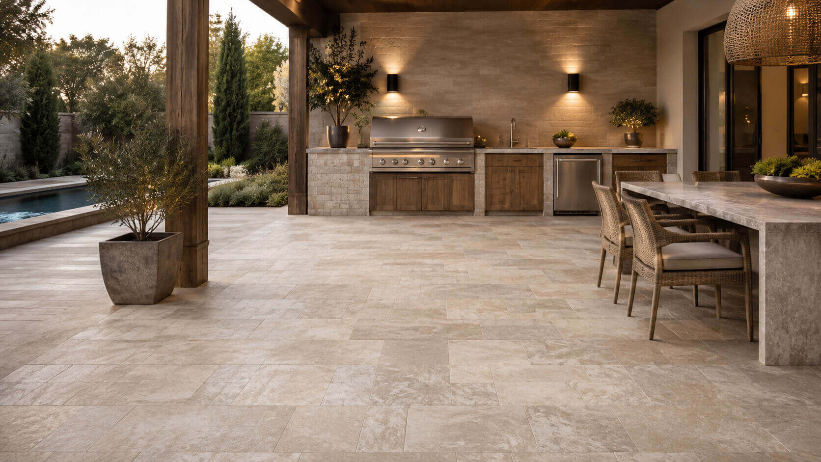 Covered outdoor kitchen with premium stone flooring, built-in grill, dining area, and poolside setting