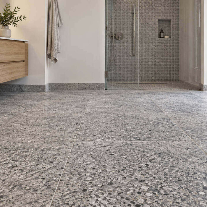 Modern bathroom with gray granite floor tiles, a floating oak vanity, and a glass-enclosed mosaic shower.