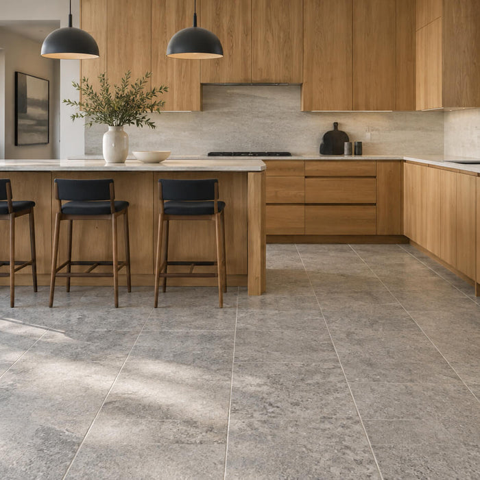 Warm oak kitchen cabinets paired with gray granite floor tiles, a central island, and soft natural daylight.