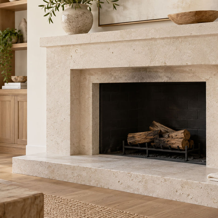 Cream limestone fireplace with light soot marks above the opening and a cleaning sponge on the hearth.