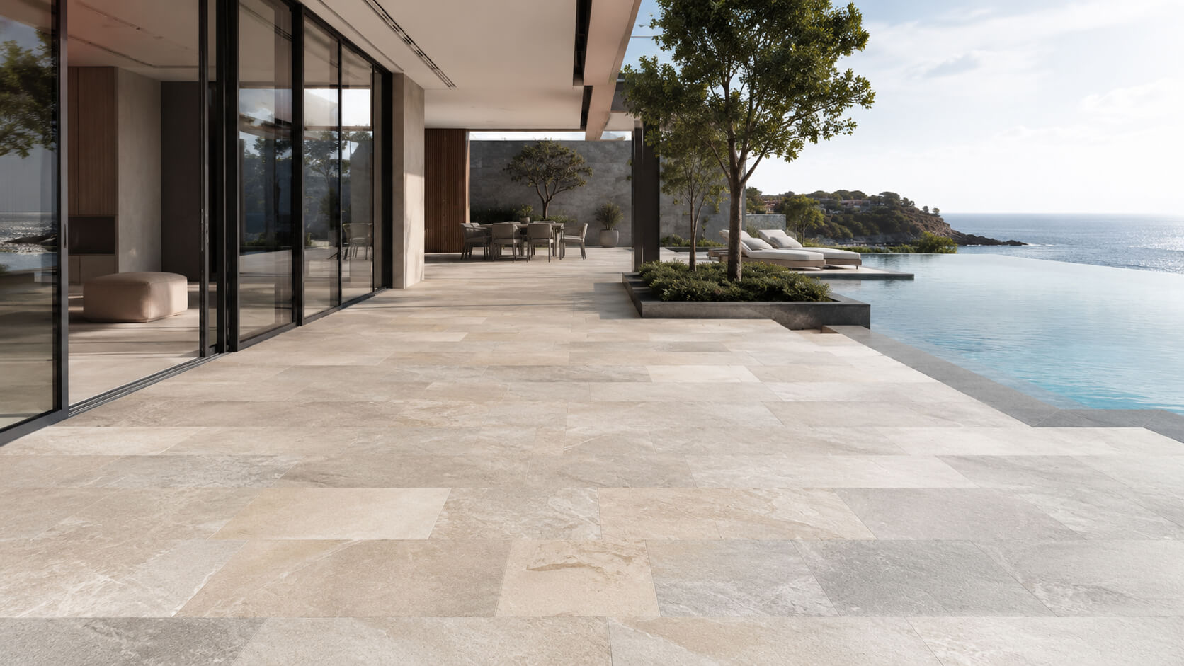 Modern villa terrace with premium natural stone pavers in warm neutral tones beside an infinity pool