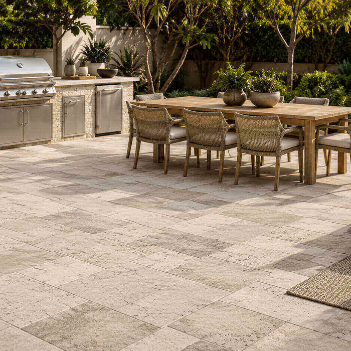 Outdoor kitchen with natural stone pavers, built-in grill, dining area, and landscaped patio