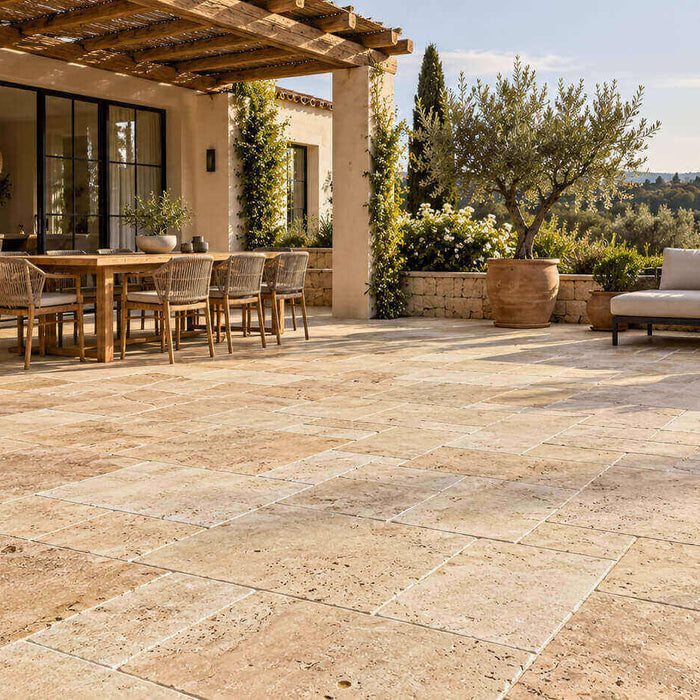 Beige travertine terrace with a wooden pergola, dining area, outdoor sofa and olive trees.