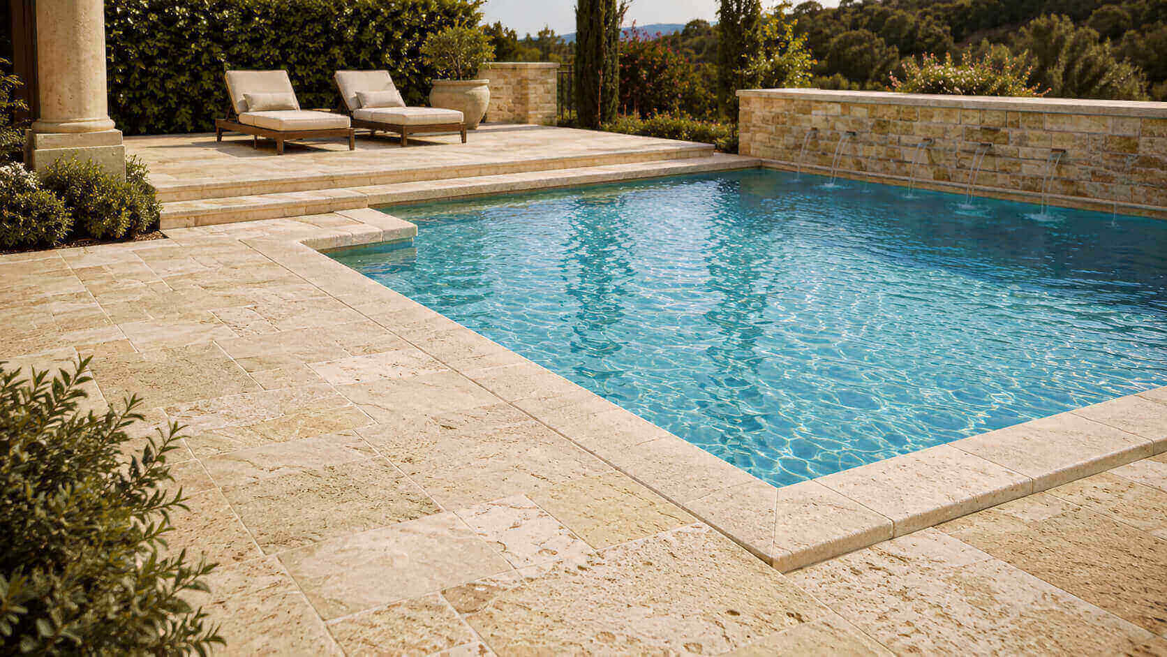 Luxury swimming pool with light travertine coping and matching travertine deck in a warm outdoor setting