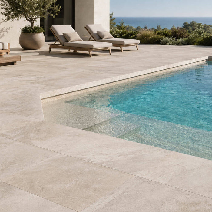 Light beige travertine pool deck around a modern outdoor pool with lounge seating and a natural resort-style patio