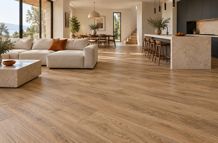 Open-plan living room and kitchen with oak-look porcelain floor tiles, ivory seating, and charcoal cabinets.