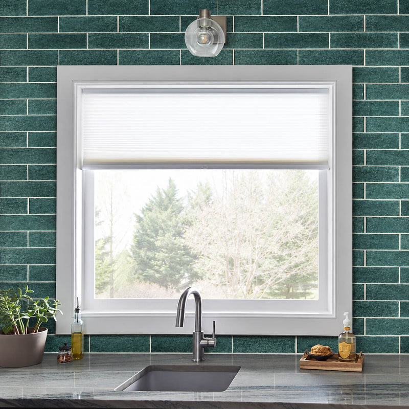 Anacapri 3x12 teal glass tile kitchen backsplash in a staggered brick pattern around a white-framed window above the sink.