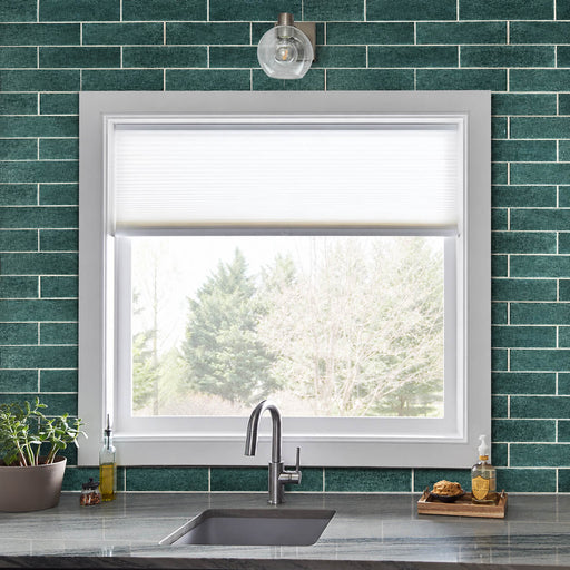 Anacapri 3x12 teal glass tile kitchen backsplash in a staggered brick pattern around a white-framed window above the sink.