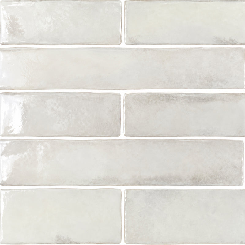 APE Savannah White 2x10 glossy ceramic tiles in a staggered layout with soft white tones and subtle gray glaze variations.