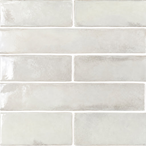 APE Savannah White 2x10 glossy ceramic tiles in a staggered layout with soft white tones and subtle gray glaze variations.