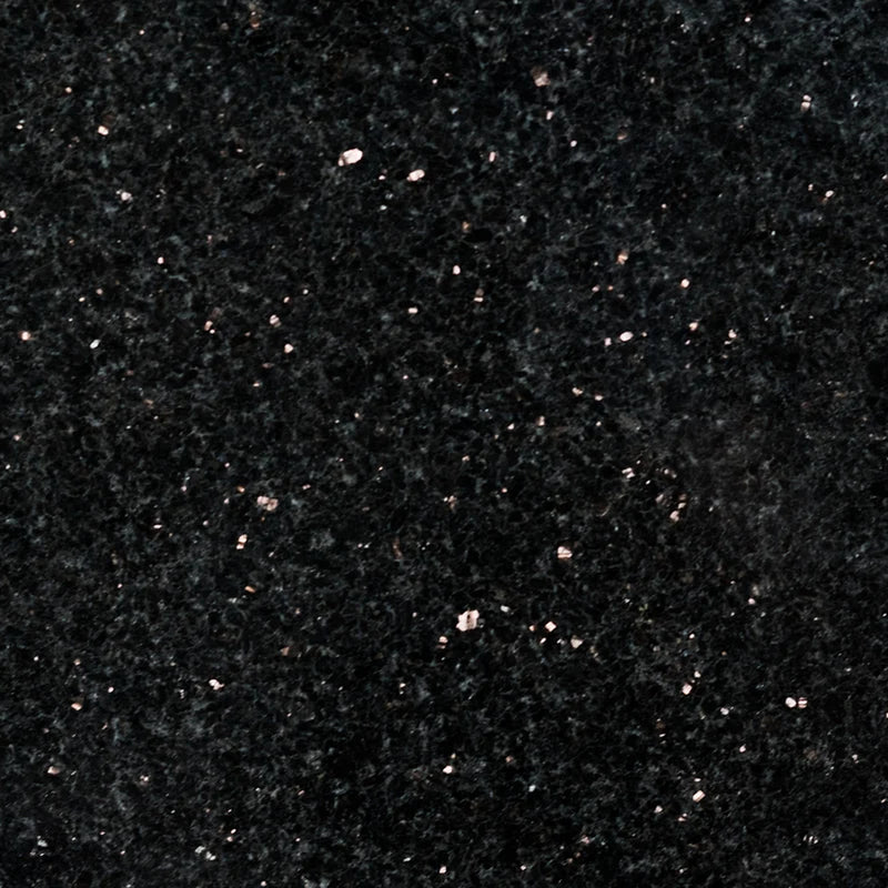 Close-up of Black Galaxy 12x24 polished granite tile with a deep black surface and scattered bronze and silver mineral flecks.