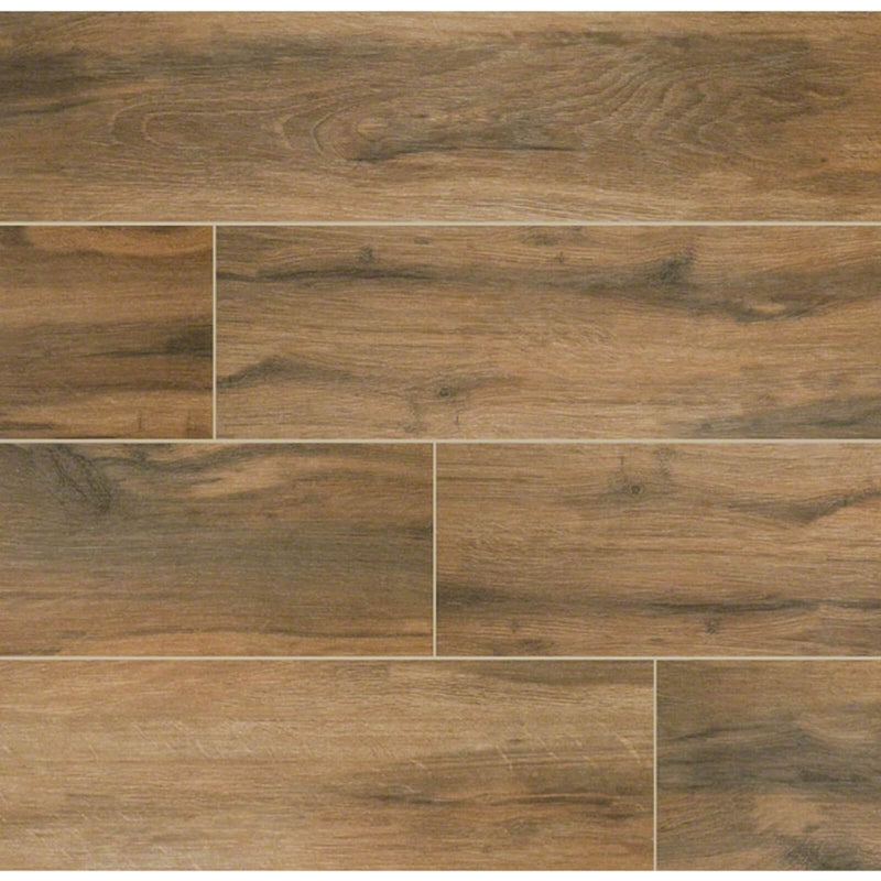 Botanica Cashew 6x24 matte porcelain wood-look tiles with warm brown grain arranged in a staggered plank layout.