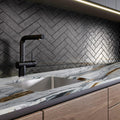 Calacatta Picasso 2cm honed marble kitchen countertop with a stainless-steel sink, black tap and dark herringbone backsplash.