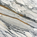 Calacatta Picasso 2cm honed marble slab with an ivory-white background and flowing charcoal-grey and golden-brown veins.