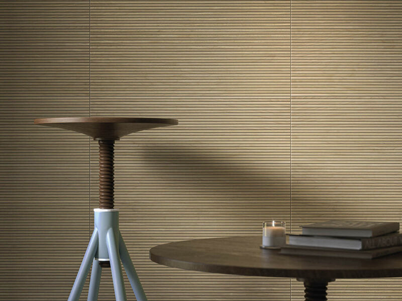 Cifre Kie Oak Matte 12x36 porcelain tile installed on a wall with horizontal oak-tone ribs, a pedestal table and a side table.