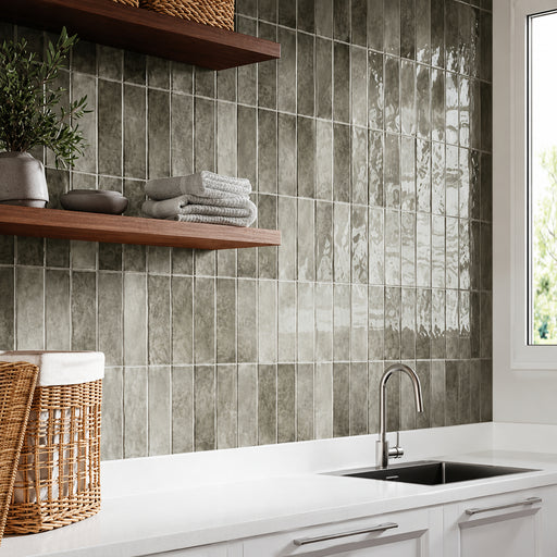 Highland Lake Olive 3x10 glossy ceramic tiles installed vertically above a white countertop with wooden shelves.