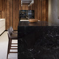 Makalu 2cm polished granite slab used for a black waterfall kitchen island with white veining and wooden cabinetry.