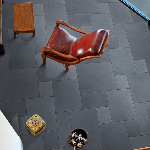 Montauk Blue Ashler Versailles pattern gauged slate tile flooring with blue-gray stone pieces, a red-brown leather chair and wooden stool.