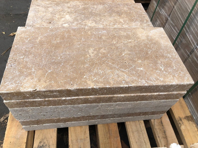 Close-up of Noce Travertine Tumbled 12 x 24 x 2 Modern Coping, in Noce tones.