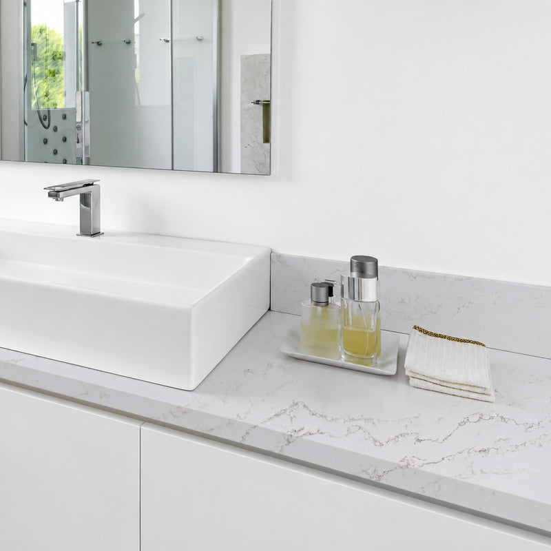 Pietra Danali Danae polished quartz bathroom countertop and backsplash with a white vessel sink and chrome faucet.