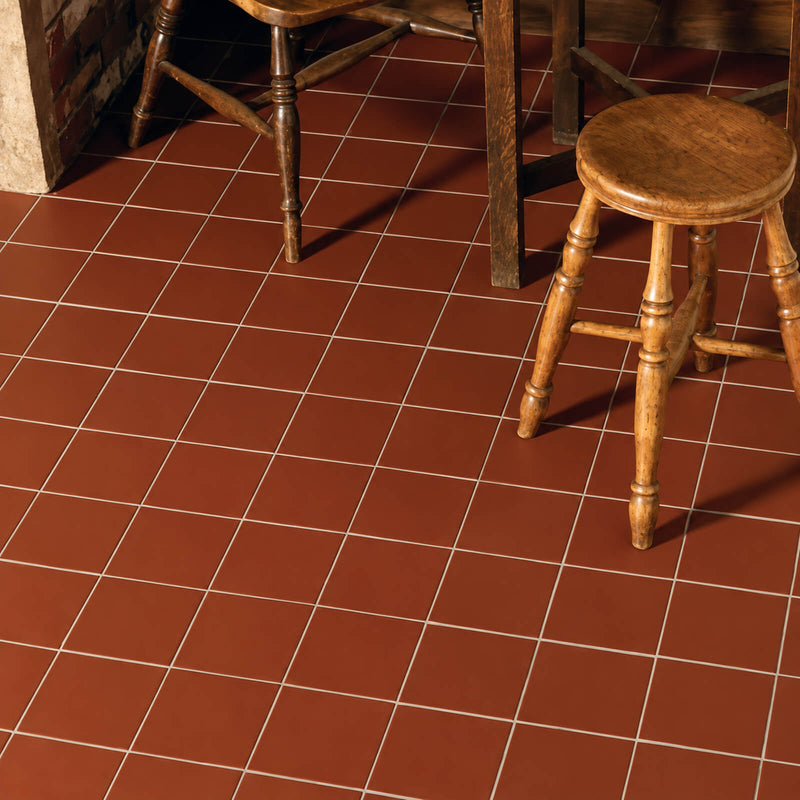 Quarry Tile Red 6x6 matte porcelain floor tiles with light grout beneath rustic wooden furniture.