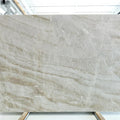 Montebello honed quartzite slab with sweeping beige and gray veins in a warehouse.