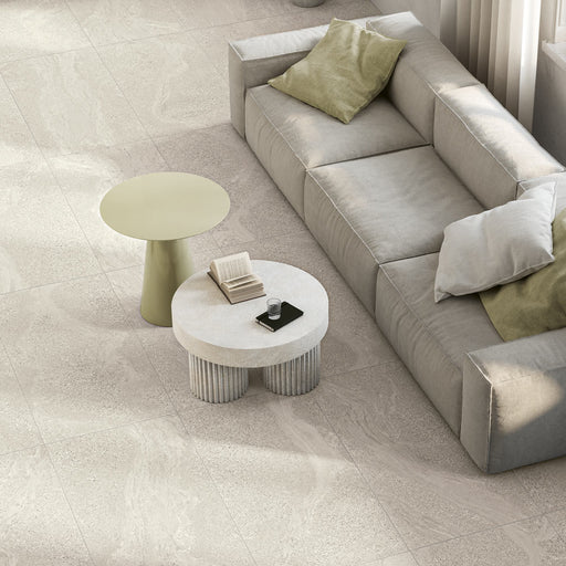 Stoneline White 12x24 Porcelain Tile flooring in a bright living room with a gray sofa, sage cushions and round accent tables.