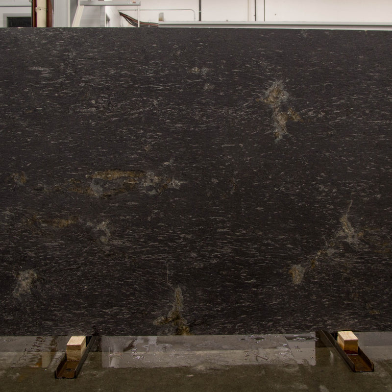 Titanium Supreme 2cm Leathered Granite Slab with a dark background and natural gray and gold veining.