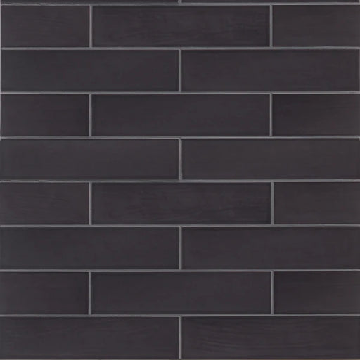 Dark charcoal Tongue in Chic Playing It Coal ceramic wall tile in a staggered subway pattern
