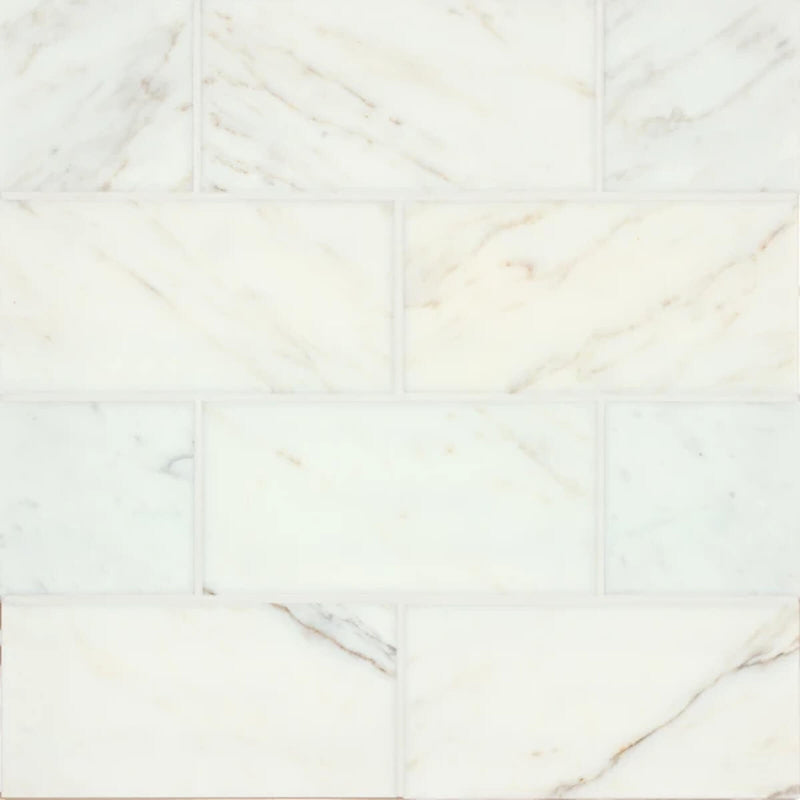 Vanity Calacatta Gold 6x12 marble tiles with subtle gold and gray veining in a staggered layout.