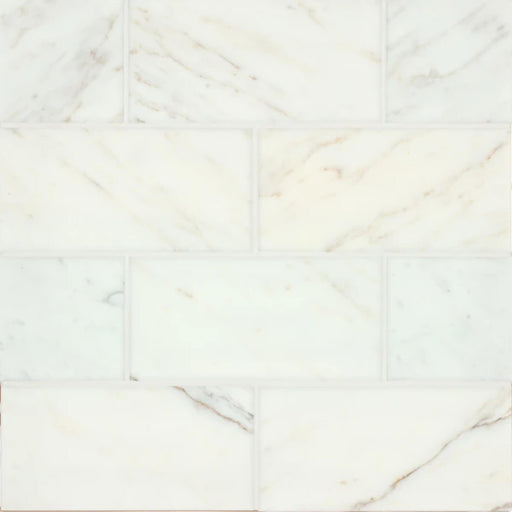 Vanity Calacatta Gold 6x12 marble tiles with subtle gold and gray veining in a staggered layout.