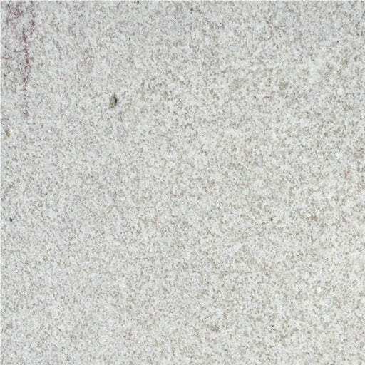 Close-up of White Fantasy granite with a pale white surface, fine gray speckling, and subtle lavender veining.