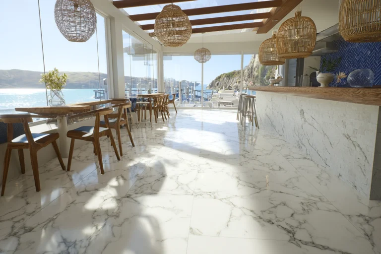 Elegant grand hallway with polished white marble flooring featuring natural gray veining, tall windows, and classic wall sconces