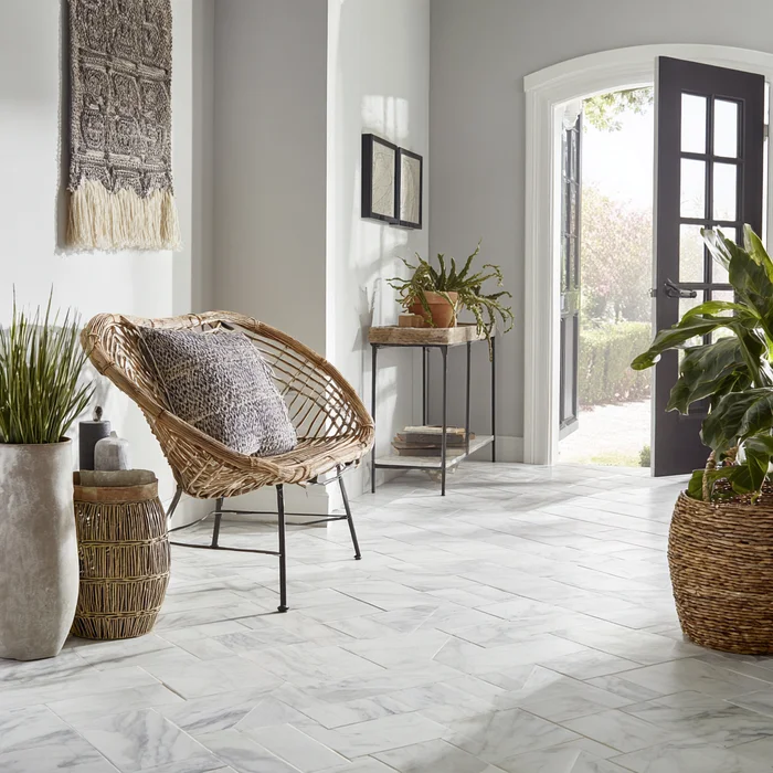 Carrara marble floor in airy lounge with wicker chair and neutral décor