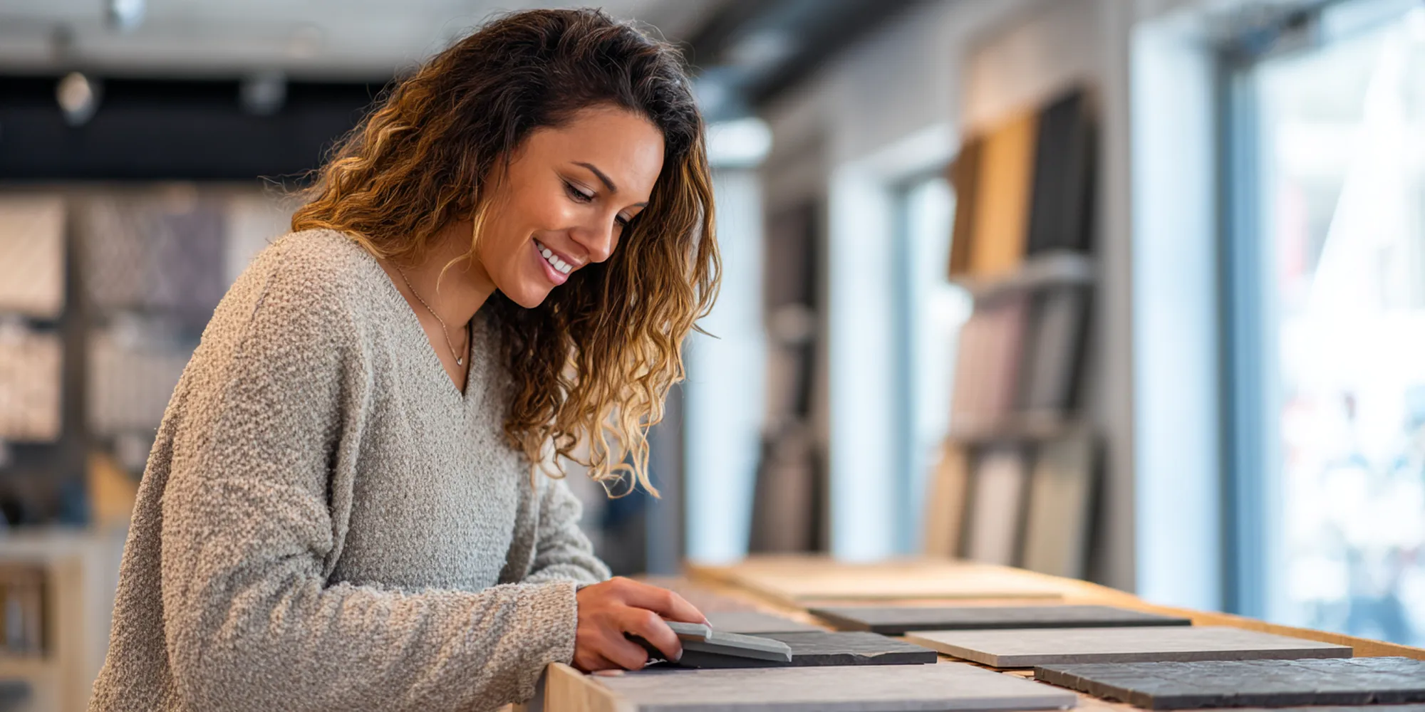 Smiling customer reviewing tile samples in bright showroom—visual reinforcing our simple, transparent pricing policy